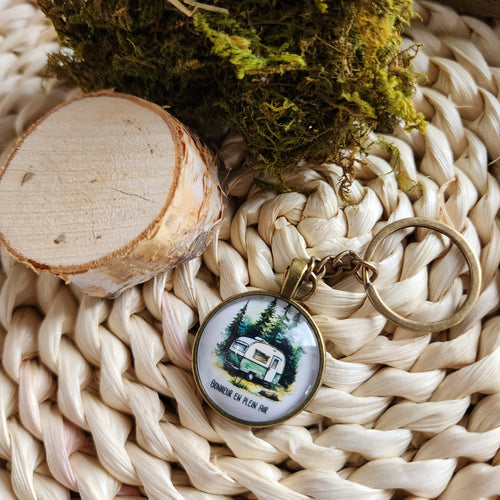 Porte-clés cabochon avec motif de camping avec une roulotte en forêt. Cabochon key ring with camping and camper design.